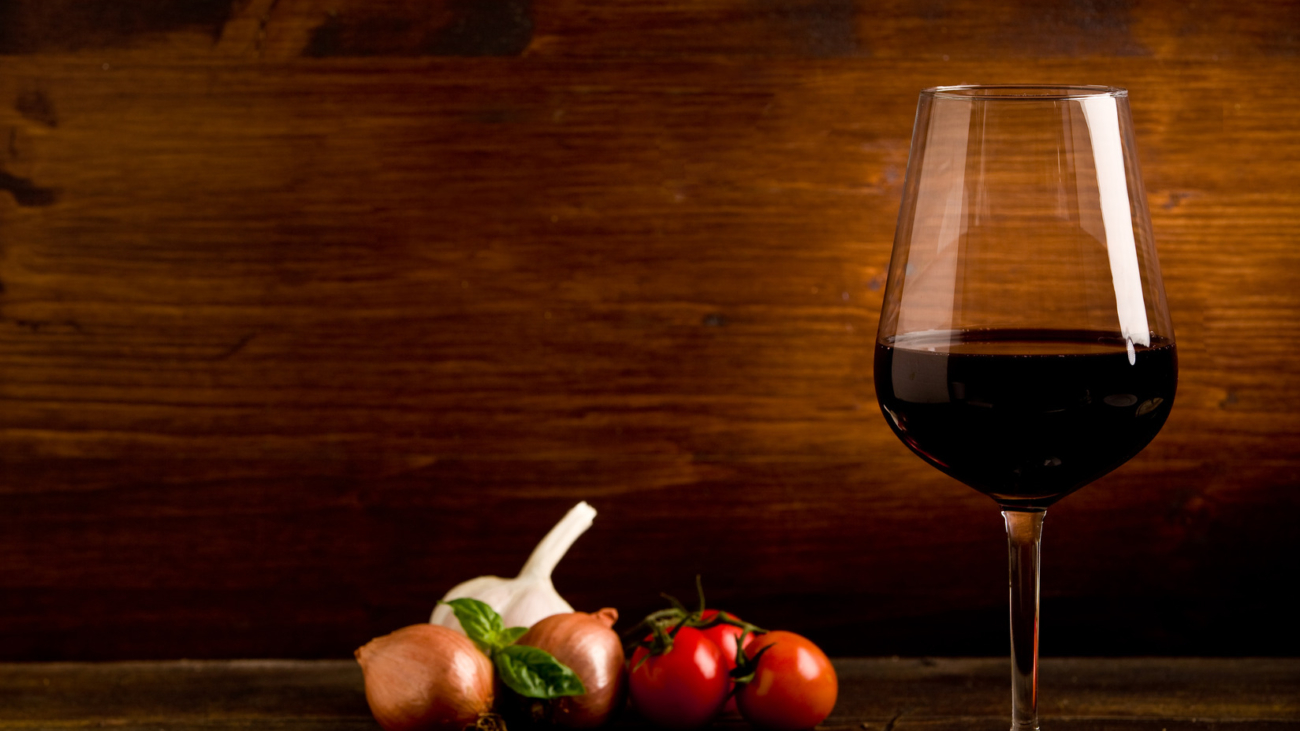 A glass of wine and some vegetables on the table