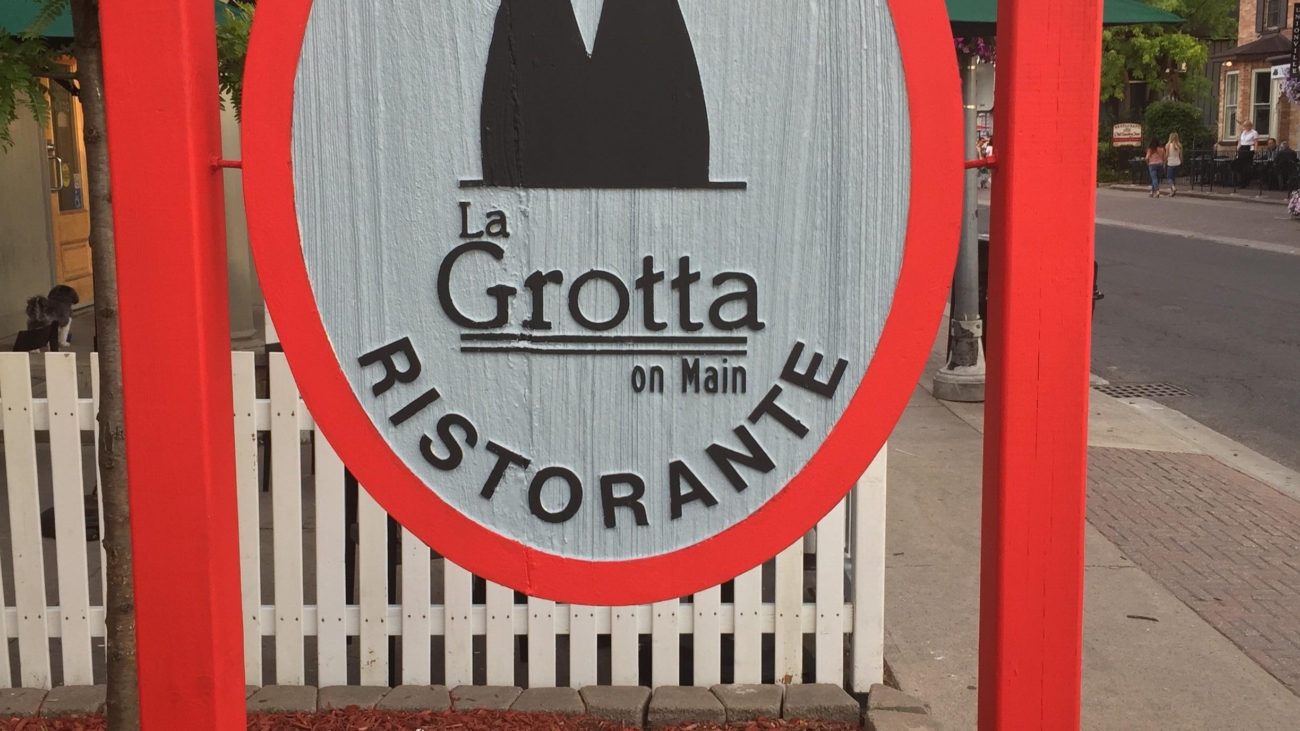 A sign for the grotto restaurant on the sidewalk.