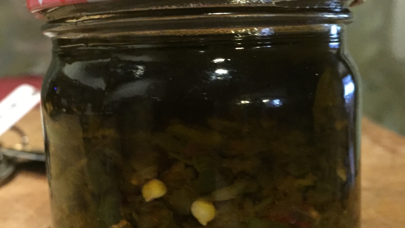 A jar of pickles sitting on top of a wooden table.