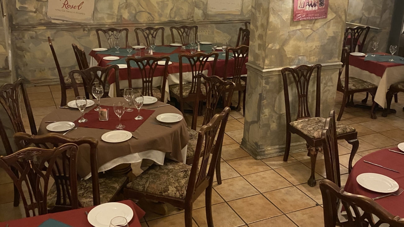 A restaurant with tables and chairs set up for dinner.
