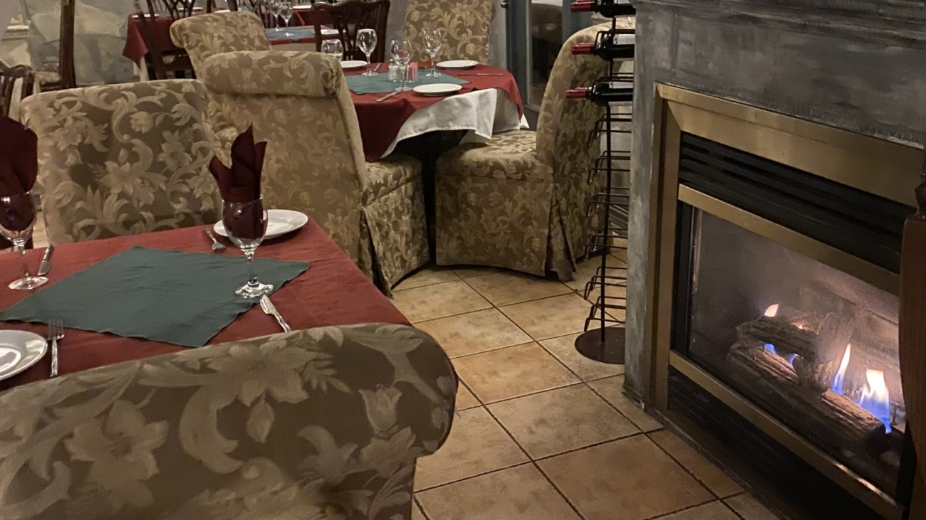 A restaurant with a fireplace and tables in the background.